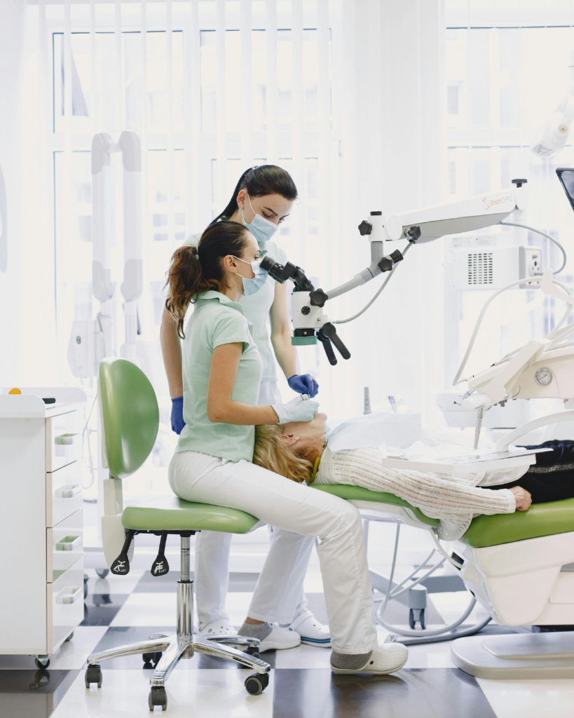 Dentista atendendo paciente utilizando microscópio